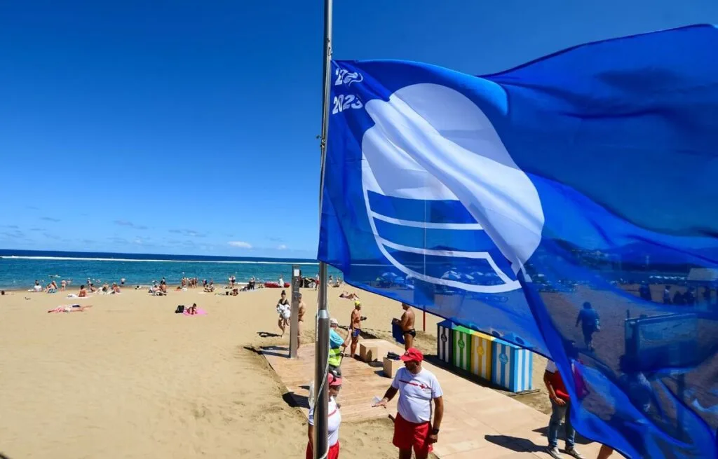 bandera azul ondeando en una playa de arena de denia
